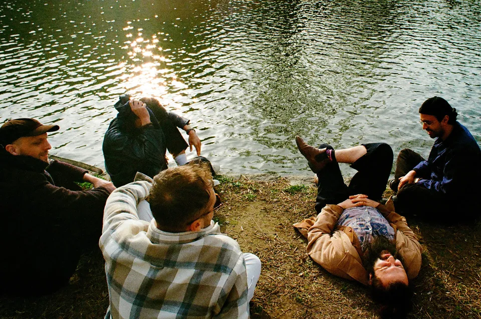 Les cinq musiciens allongés au bord de l’eau, au soleil